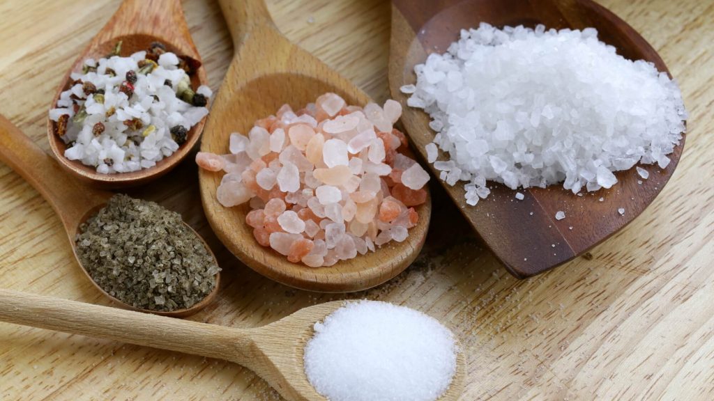 Cinco colheres de pau com diferentes tipos de sal